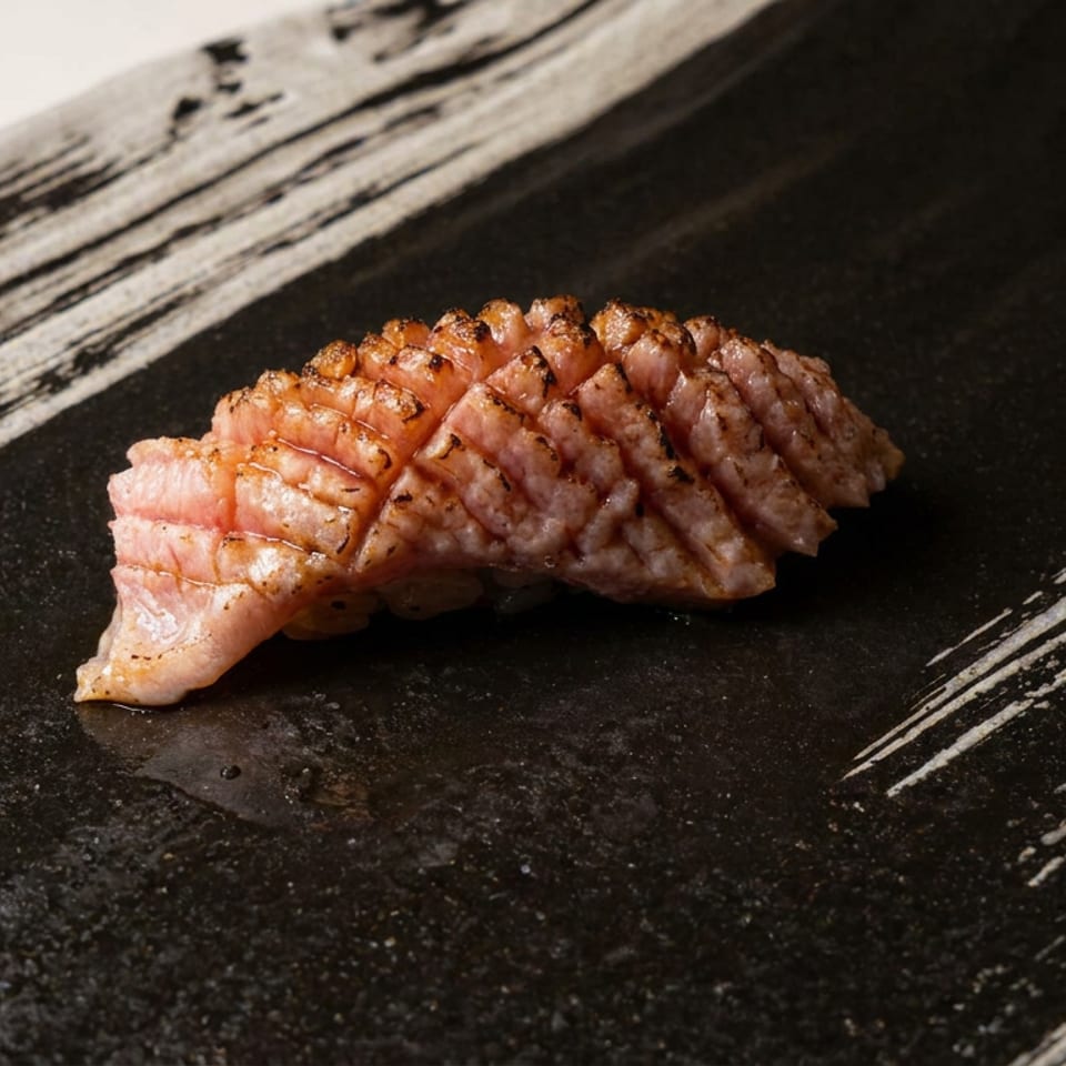Seared, crosshatched fish fillet served on a rustic black plate with a small garnish.